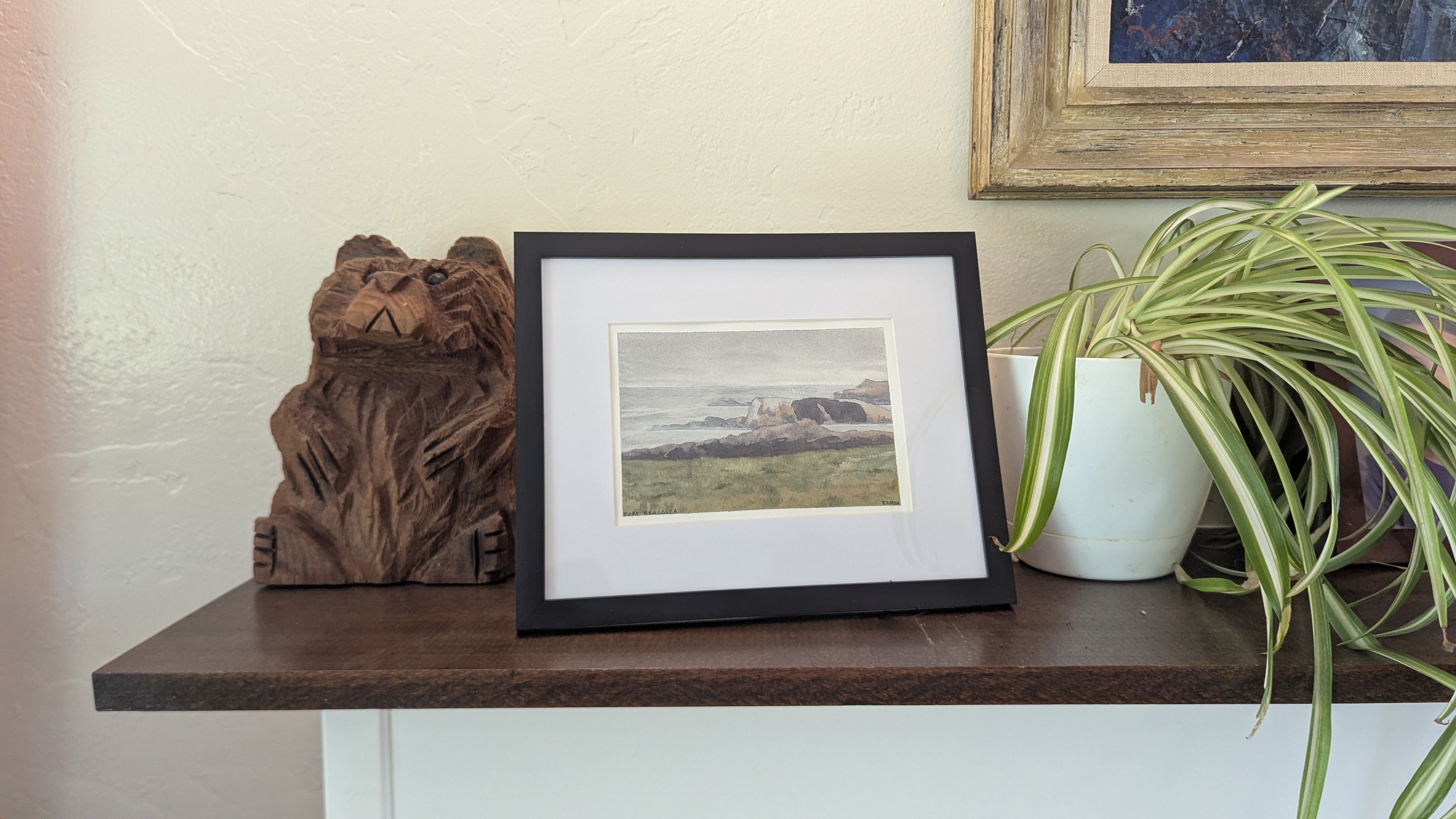 Watercolor painting of the beach at Fort Bragg, CA sitting on a mantel.